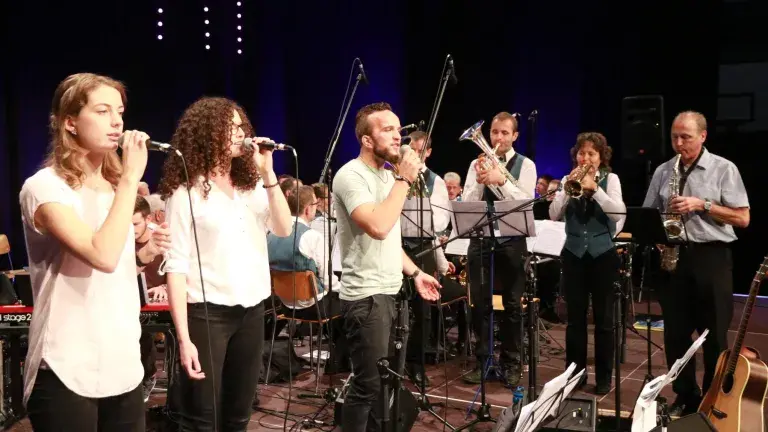 Jugendband spielt auf einer Bühne mit verschiedenen Instrumenten.